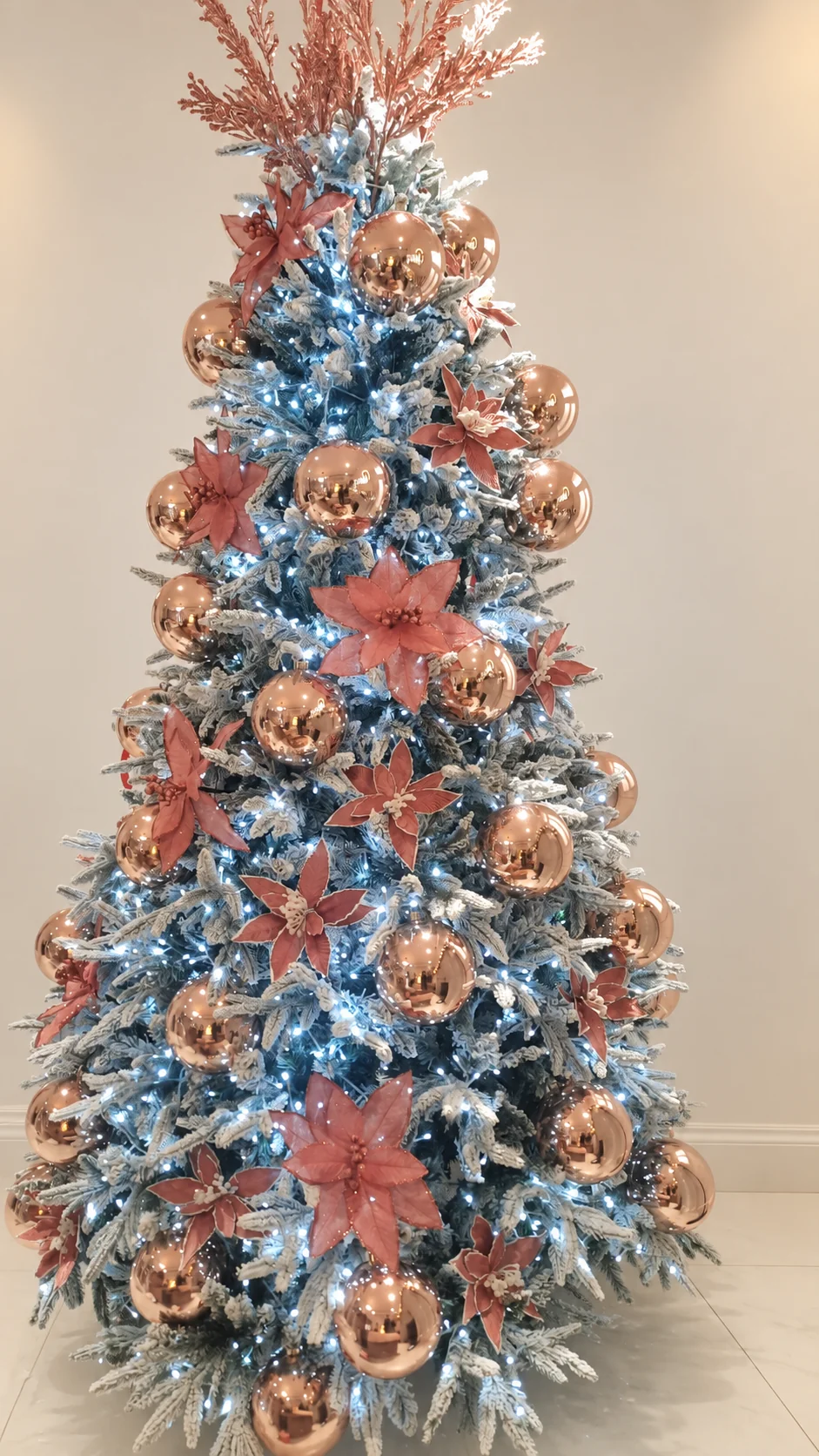 Árbol nevado con flores y esferas en rosa cobrizo