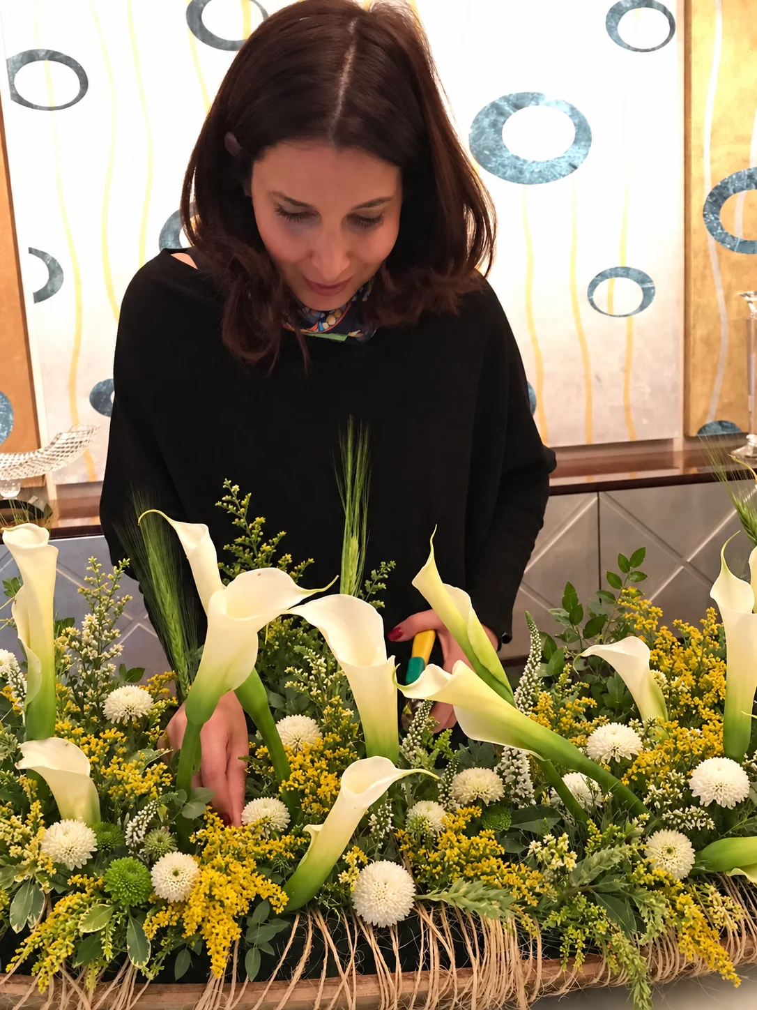 Karina Barhumi creando un arreglo floral en forma de barco con hoja de palmera