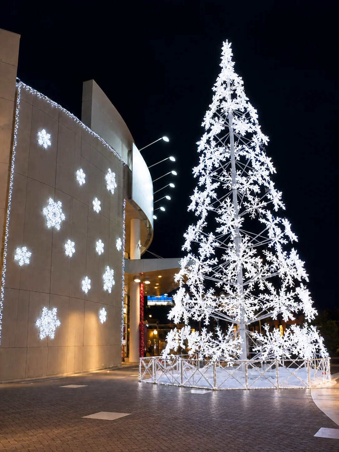 Árbol monumental blanco de copos de nieve con reja iluminada