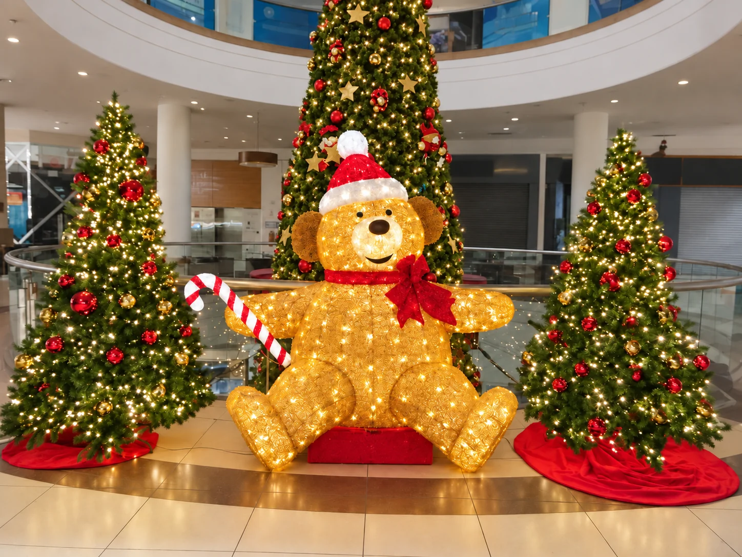 Montaje navideño de gran formato con oso iluminado y tres árboles llenos de luces